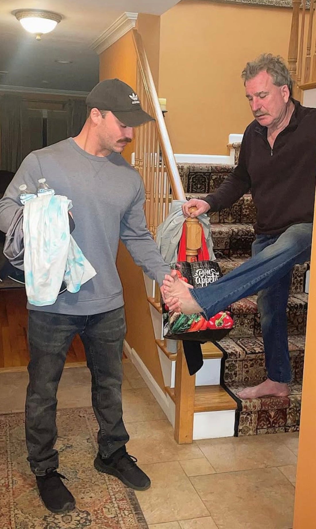 Chris McGrath helping his father on the stairs — a moment of love, strength, and legacy that inspired the Daddy Mustache brand