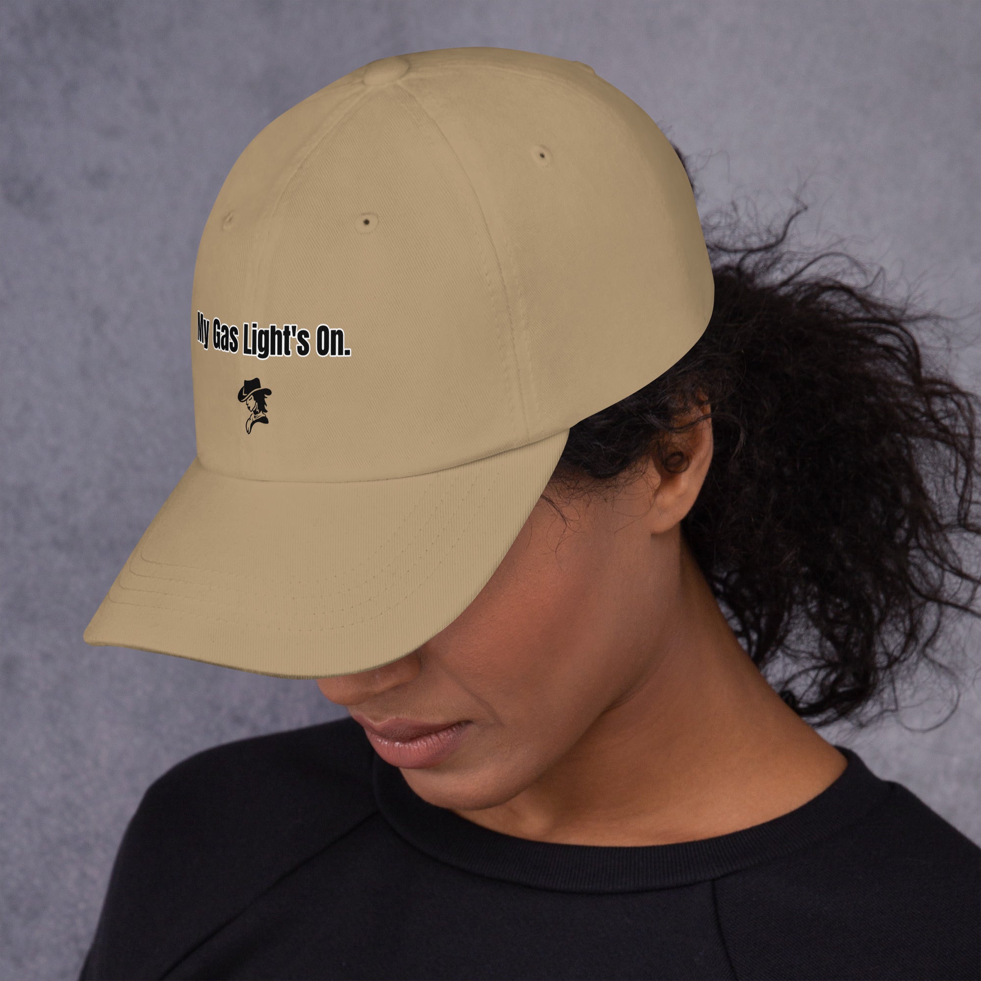 Person wearing a beige cap with text and a logo on a gray background