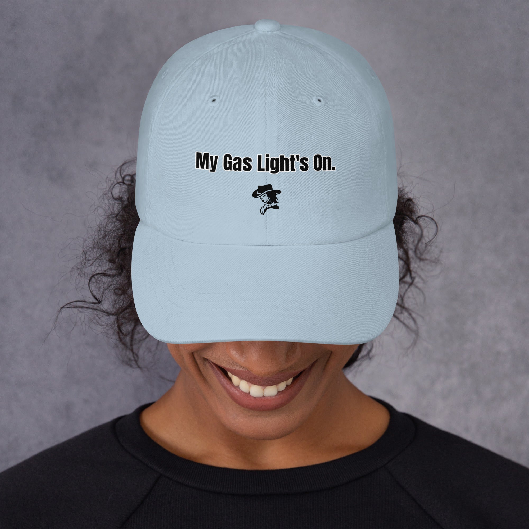 Light blue cap with 'My Gas Light's On.' text worn by a person against a gray background