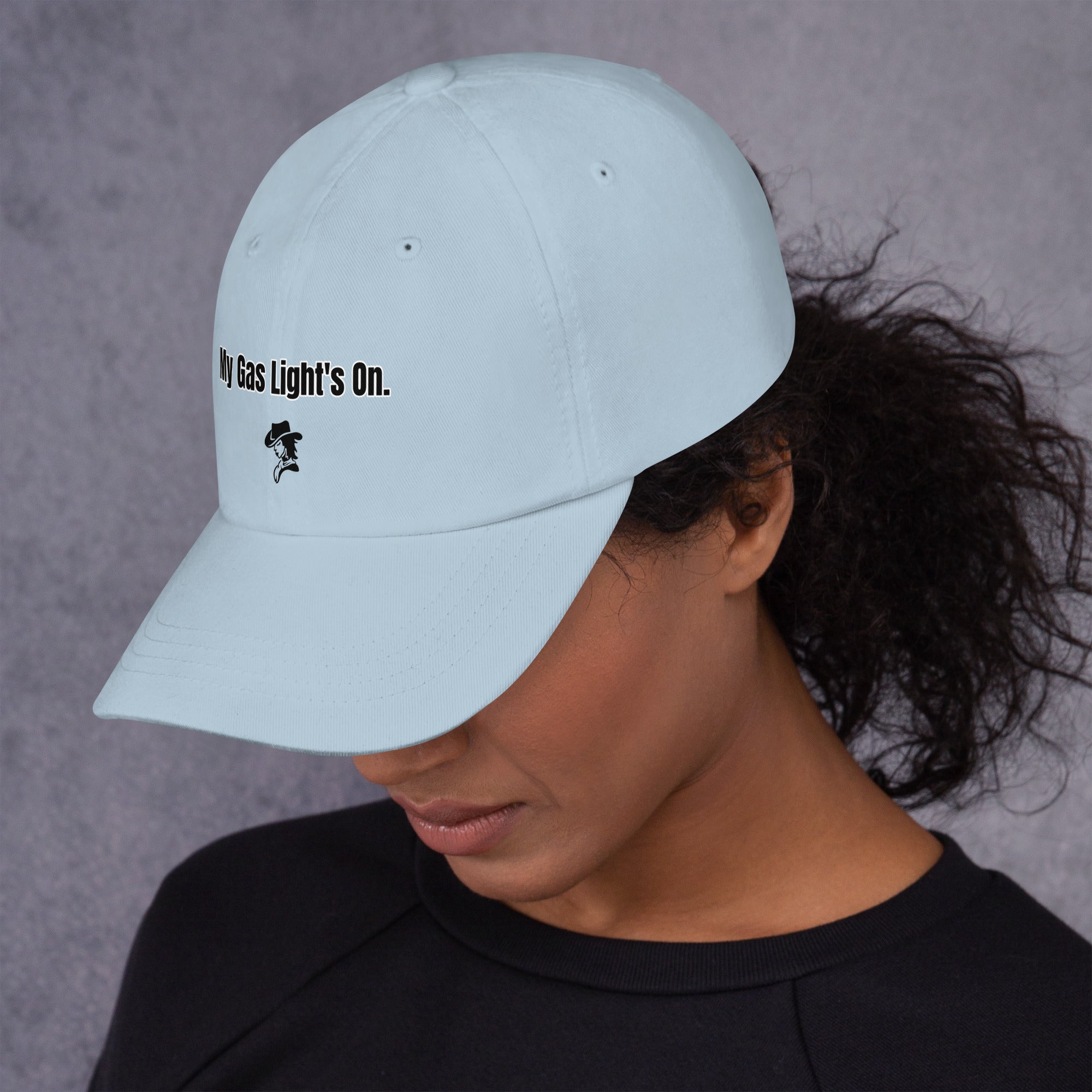 Person wearing a light blue cap with text and a logo on a gray background