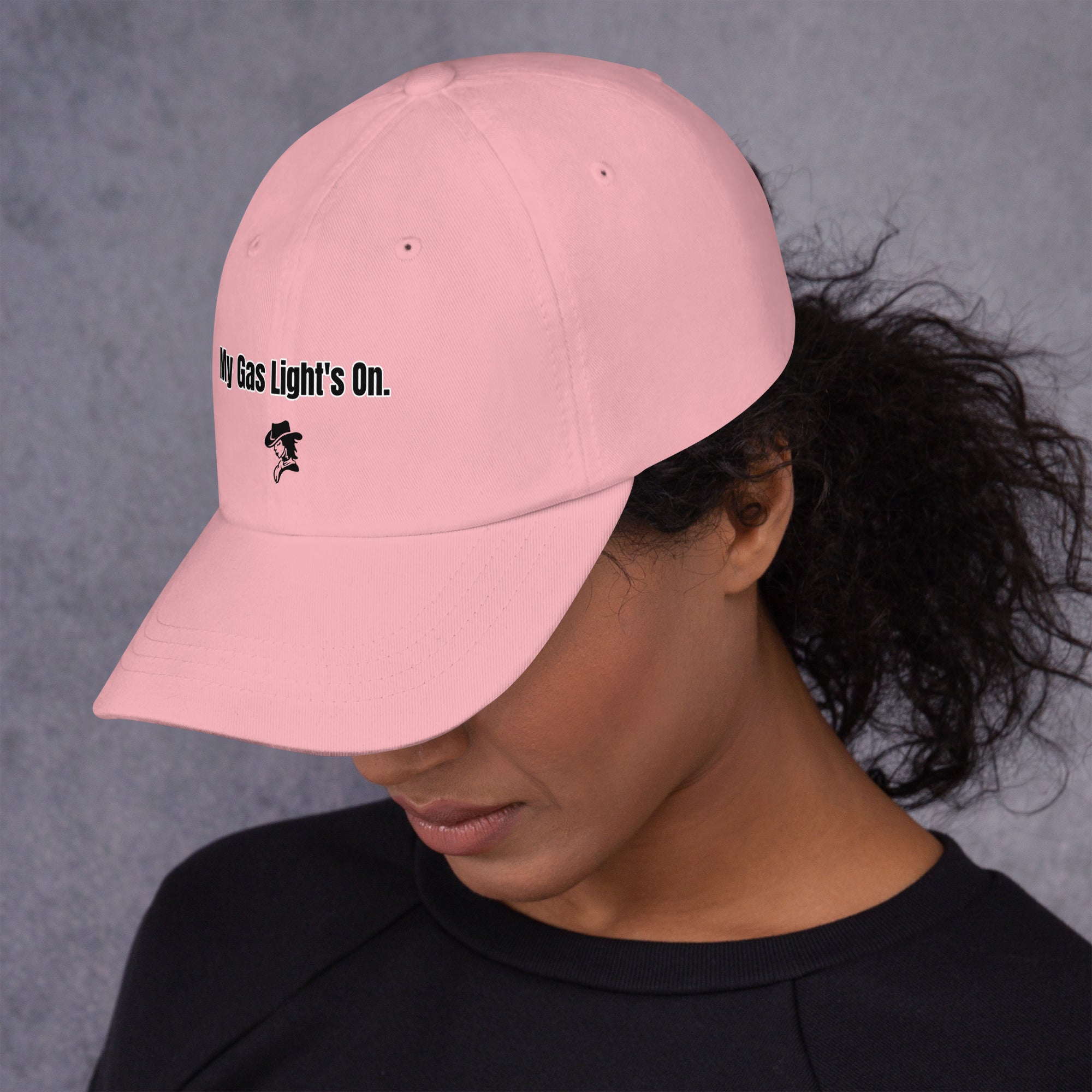 Person wearing a pink cap with text and a logo on a gray background