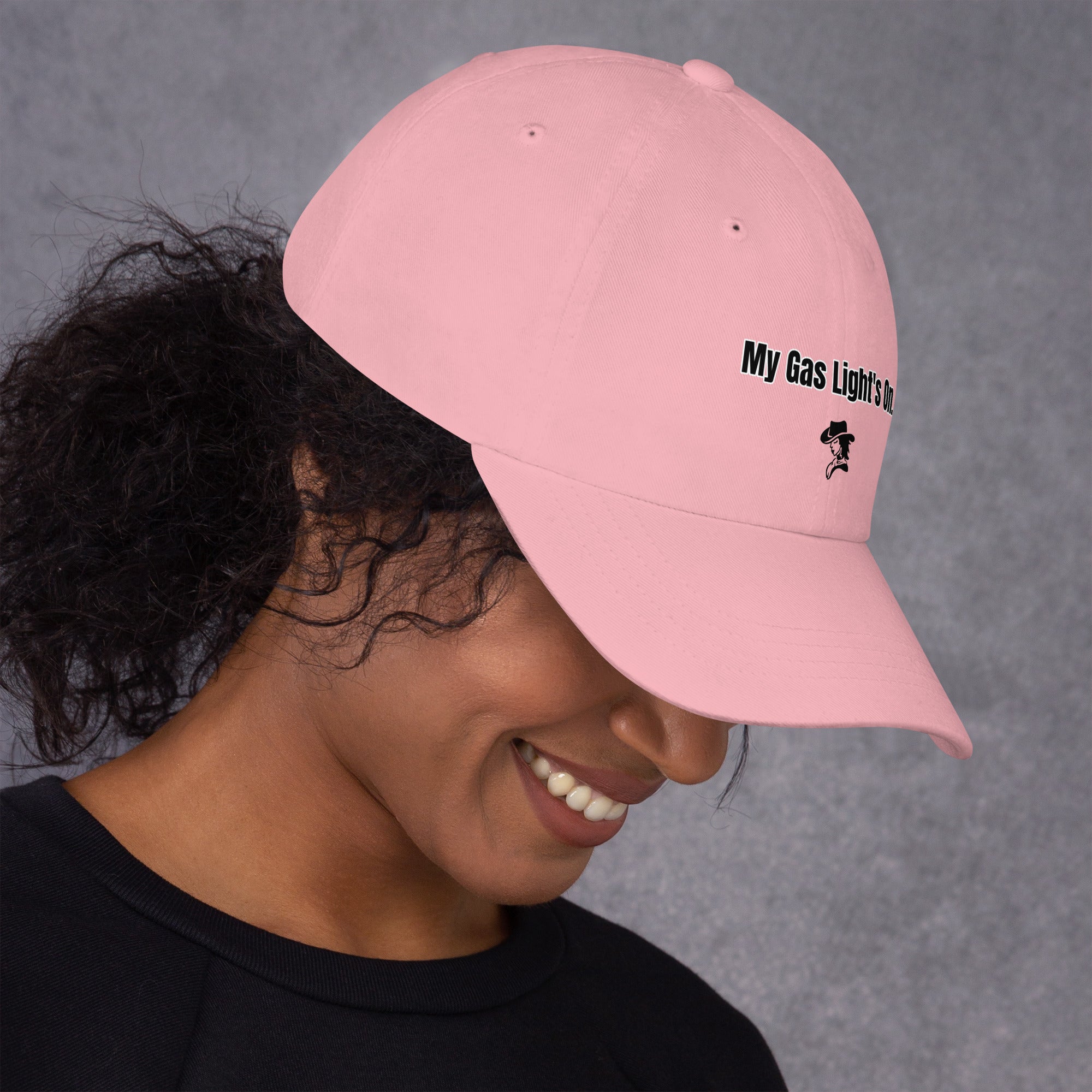Person wearing a pink cap with text and a logo on a gray background