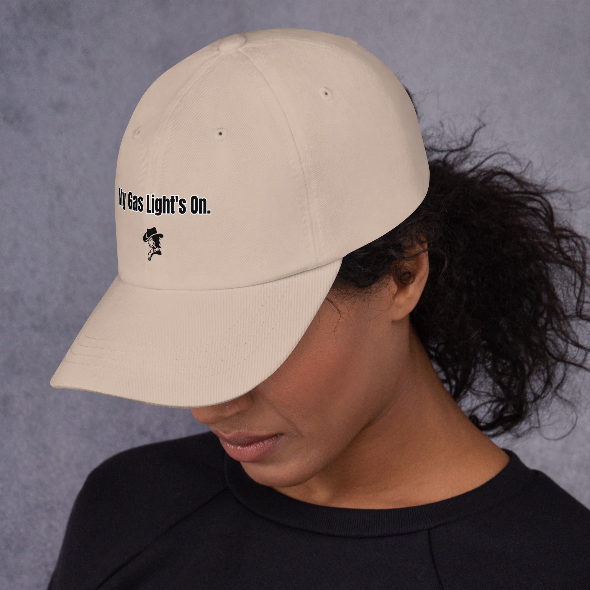 Person wearing a beige cap with text and a logo on a gray background